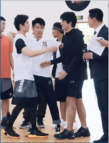 a man wearing a ny t-shirt is being hugged by another man