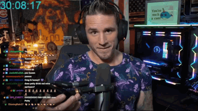 a man wearing headphones holds a microphone in front of a screen that says 30 08 17