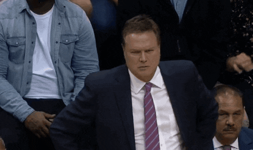 a man in a suit and tie sits in a crowd of people