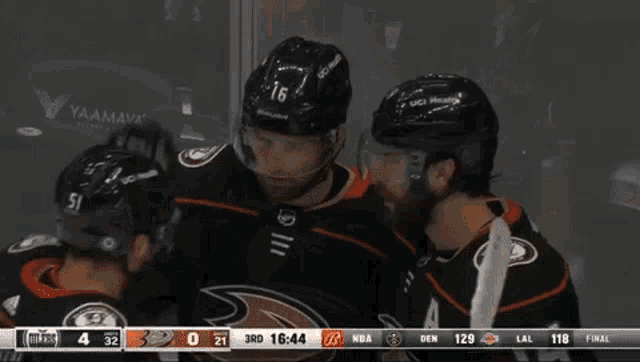 a hockey player with the number 16 on his helmet is hugging his teammates