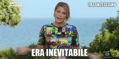 a woman in a sequined top is standing in front of a body of water with the words era inevitabile above her