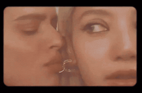 a close up of a woman kissing another woman 's cheek