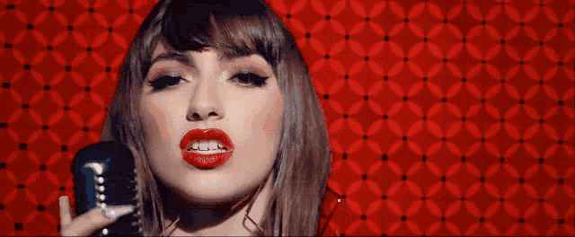 a woman singing into a microphone with red lipstick