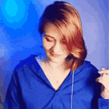 a woman with red hair wearing a blue shirt and headphones
