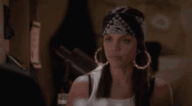 a woman wearing a bandana and hoop earrings
