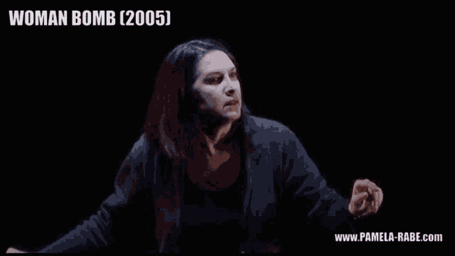 a woman in a black jacket stands in front of a black background that says woman bomb 2005