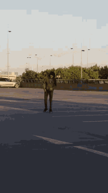 a man is standing in a parking lot looking down