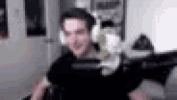 a man wearing headphones and holding a stuffed animal is sitting in front of a computer .