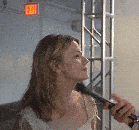 a woman is being interviewed by a man with an exit sign in the background