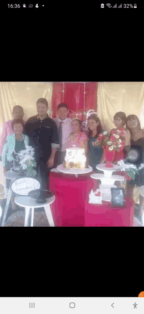 a group of people posing in front of a cake