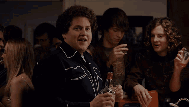 a man in a cowboy jacket holds a bottle of vodka in his hand