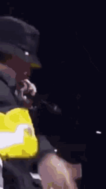 a man in a hat is singing into a microphone while another man holds his head .