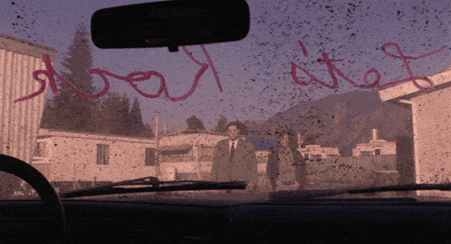 a man in a suit and tie stands in front of a dirty windshield with the words " do not enter " written in red