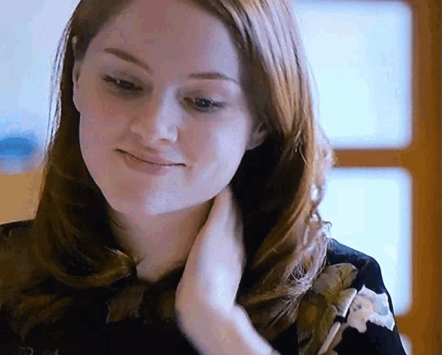 a close up of a woman 's face with a floral shirt on