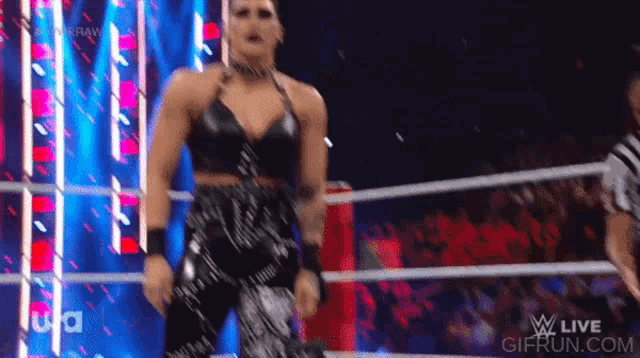 a woman is dancing in a wrestling ring while a referee watches