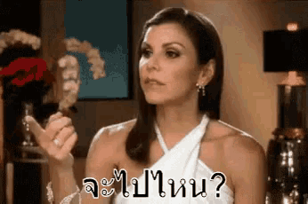 a woman in a white dress is making a funny face and asking a question in thai .