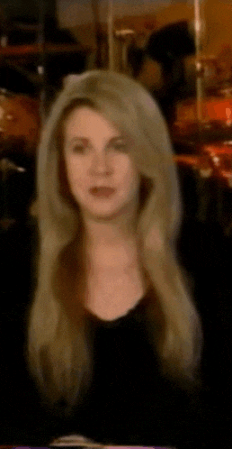 a woman with blonde hair and a black shirt is looking at the camera