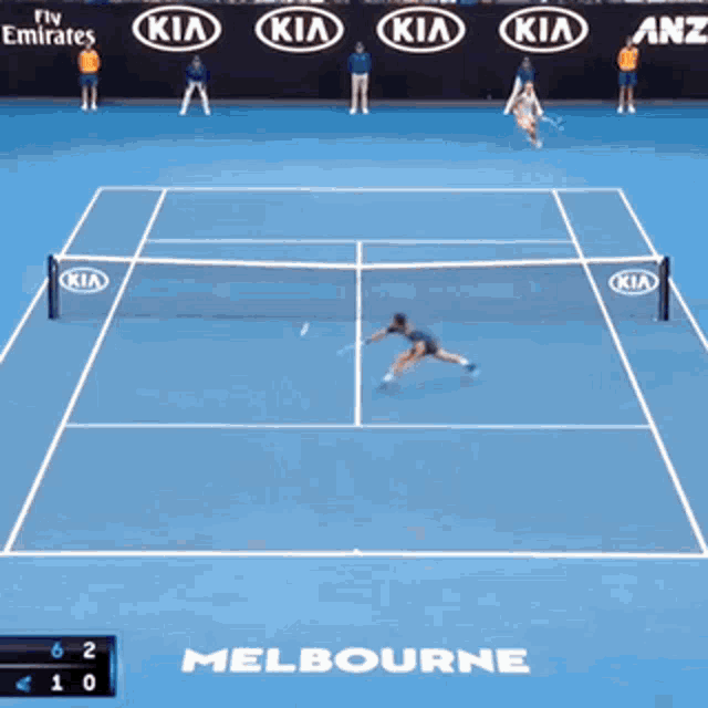 a man is holding a tennis racquet on a tennis court sponsored by kia and kia emirates