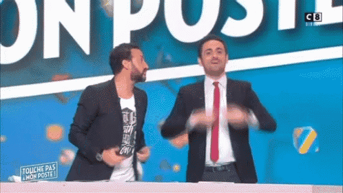 two men are dancing on a stage in front of a sign that says touche pas a mon poste .