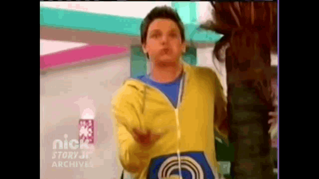 a man in a yellow hoodie is standing next to a woman .