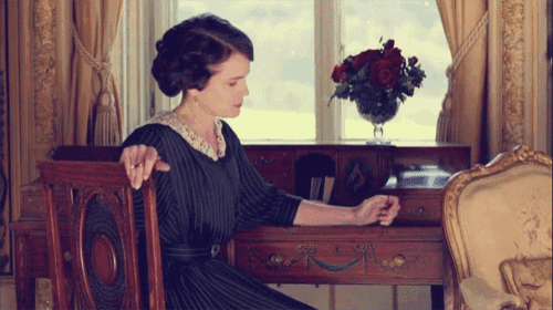 a woman is sitting at a desk with a vase of flowers in front of her