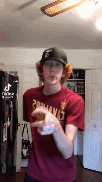 a young man wearing a red shirt and a black hat is pointing at something