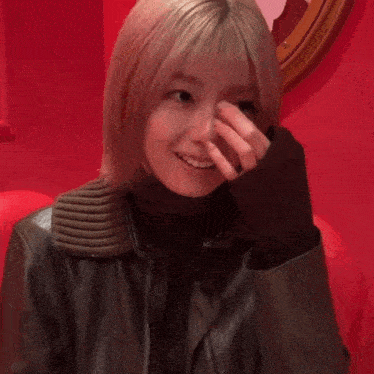 a woman covering her nose with her hand while wearing a black jacket