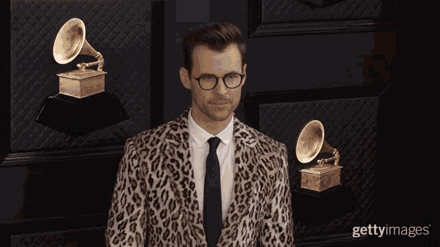 a man wearing a leopard print suit and tie is smiling