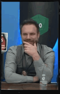 a man is sitting at a table with a bottle of water