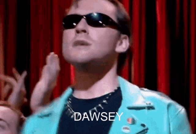 a man wearing sunglasses and a blue jacket with the word dawsey written on it