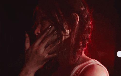 a woman with long red hair is standing in a dark room