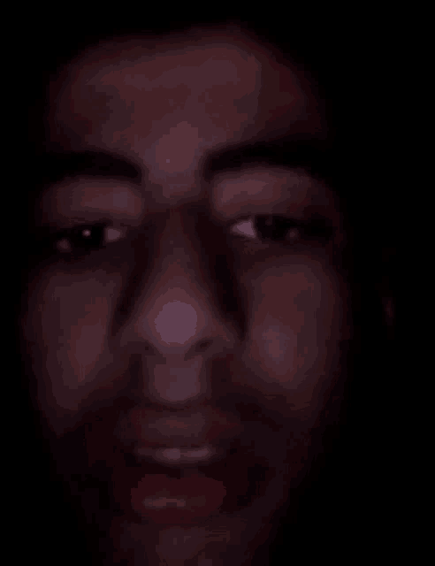 a close up of a man 's face in a dark room