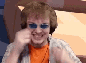 a man wearing headphones and blue sunglasses is making a face .