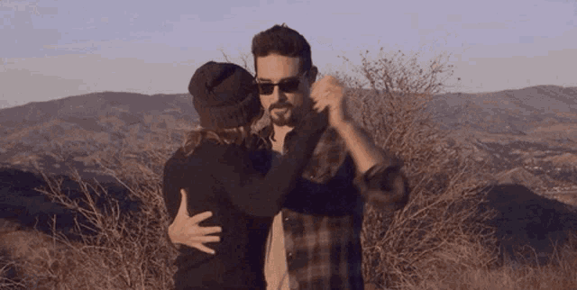 a man and woman dancing in front of mountains
