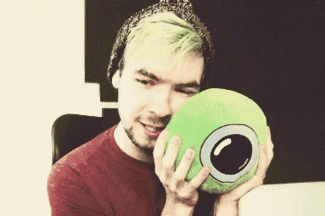 a man with green hair is holding a green pillow in his hands