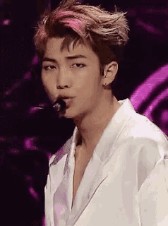 a young man in a white jacket is singing into a microphone .