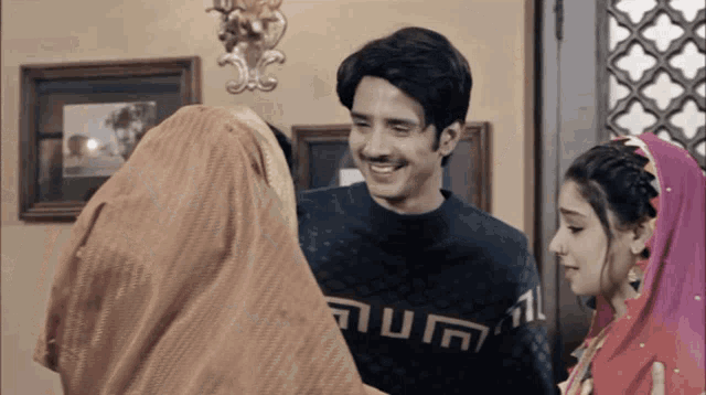 a man wearing a sweater that says ' aum ' on it is smiling