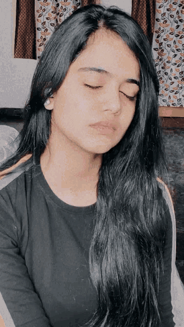 a woman with her eyes closed and a black shirt on