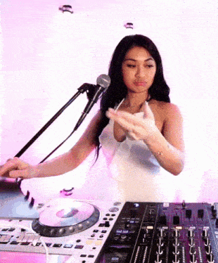 a woman in a white dress is playing a dj mixer