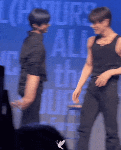 a blurry photo of two men dancing in front of a sign that says hours