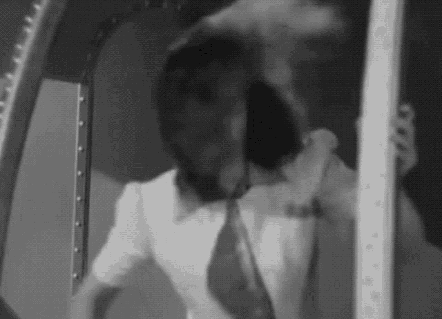 a woman in a white shirt and tie is standing in a room