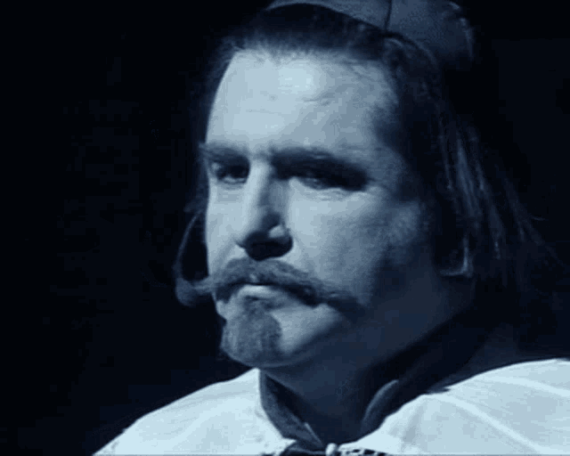 a man with long hair and a mustache is wearing a white shirt