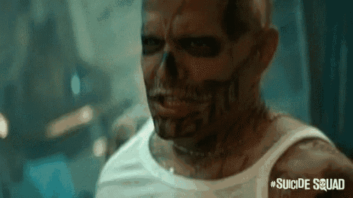 a man with a skull painted on his face is standing in a dark room .
