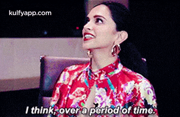 a woman in a red dress is sitting in a chair and smiling while talking about a period of time .