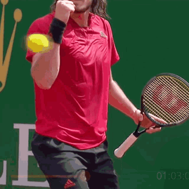 a man in a red shirt is holding a tennis racquet in his right hand .