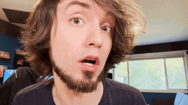 a man with long hair and a beard looks surprised with his mouth open
