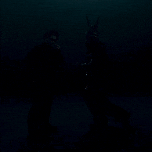 a man wearing sunglasses stands next to a man wearing a helmet with horns on it
