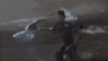 a person is holding a sword that is glowing in the dark .