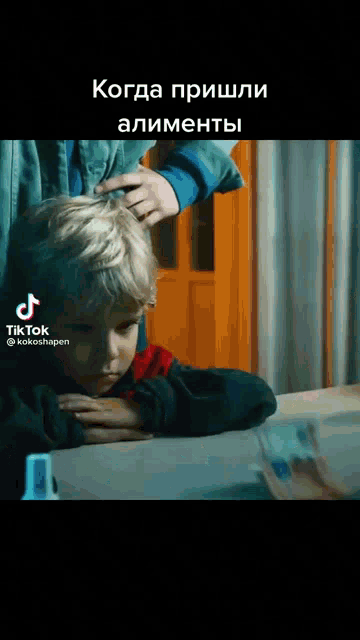 a young boy is sitting at a table while a man brushes his hair in a tiktok video
