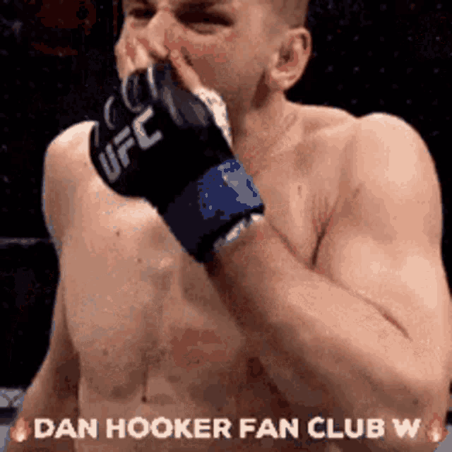 a shirtless man wearing a pair of ufc gloves is covering his nose .